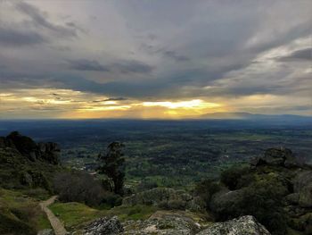 Scenic view of landscape against dramatic sky during sunset