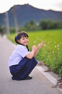 Full length of cute girl crouching on road