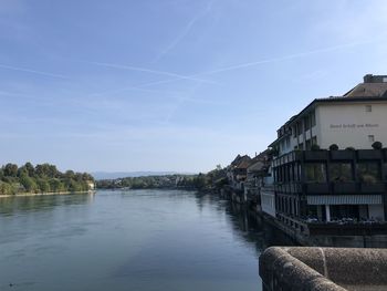 Scenic view of river by buildings against sky