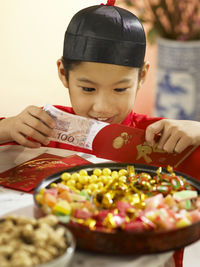Close-up of teenage boy in traditional clothes holding money