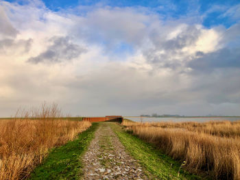 Road amidst field against sky