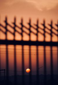 Close-up of silhouette fence against orange sky