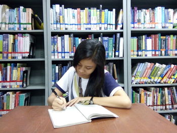 Young woman reading book in library