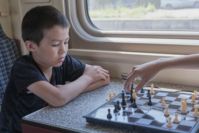 Side view of boy sitting on window sill