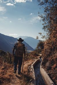 Rear view of man walking on mountain against sky