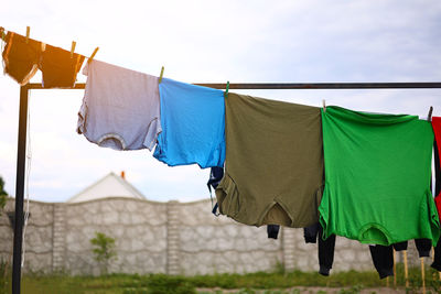 Clean colorful clothes t shirts hanging to dry on a laundry line outdoors, housework