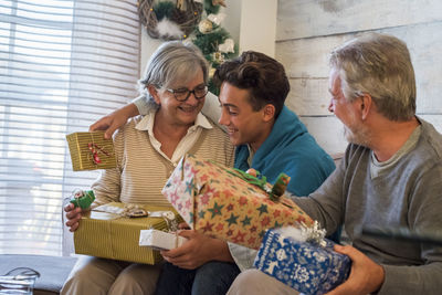 Smiling grandparents giving gift to grandson at home