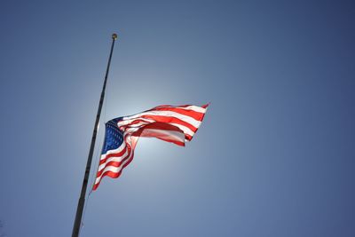 Low angle view of american flag against clear blue sky