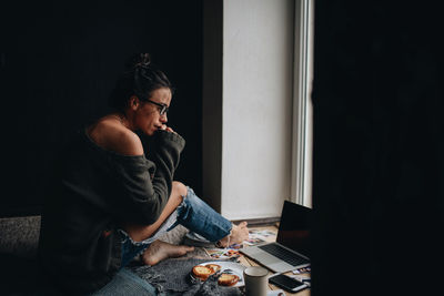 Young woman looking away while sitting at home