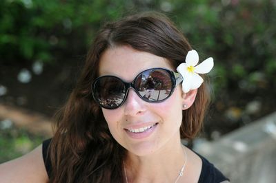 Close-up of smiling woman wearing sunglasses and flower