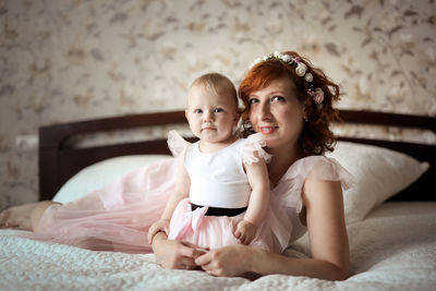 Gentle mother and daughter on the bed in a real room, the concept of motherhood and affection