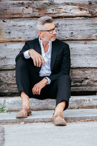 Portrait of businessman sitting against wall