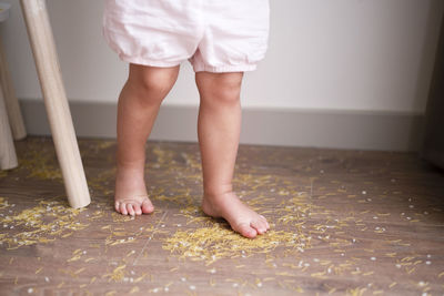 Toddler girl legs standing on messy floor after playing with grain, nuts, pasta and rice