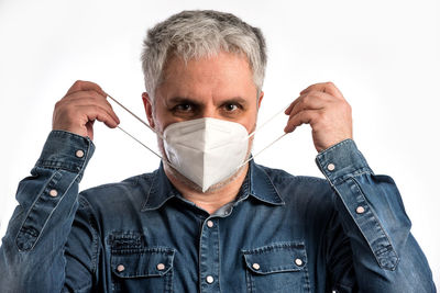 Portrait of man covering face against white background