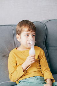 Little boy sits with an inhalation mask during cough and bronchitis. 