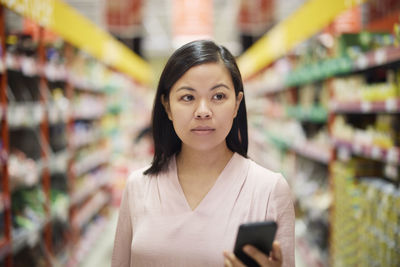 Woman looking at prices during inflation while doing shopping in supermarket