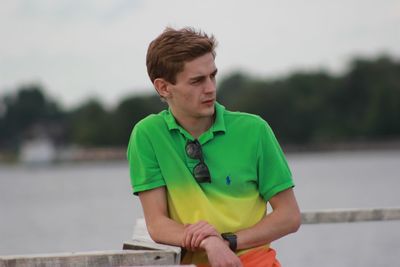 Young man looking away while standing outdoors
