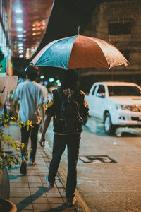 Rear view of people walking on wet street