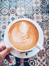 Person holding cappuccino served on table