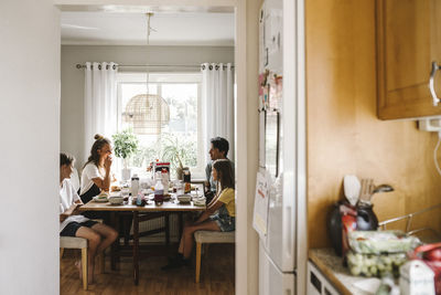 Happy family eating breakfast seen through doorway of kitchen at home