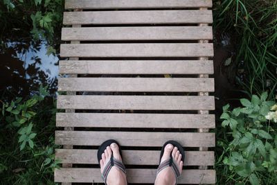 Low section of man standing on wooden boardwalk