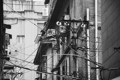 Low angle view of electric pole against buildings in city