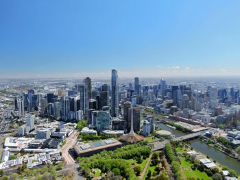 High angle view of modern buildings in city against blue sky