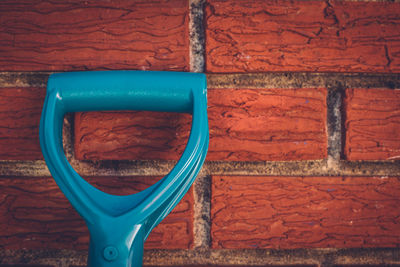 Close-up of shovel by brick wall