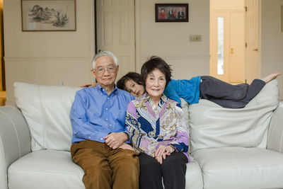 Portrait multi ethnic asian grandparents and grandson on couch at home