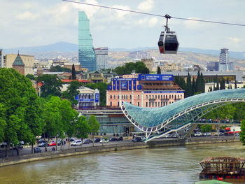 Bridge over river by buildings in city against sky