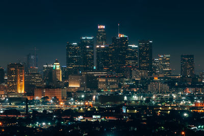 Illuminated buildings in city against sky at night