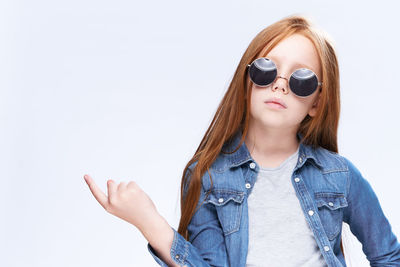 Young woman wearing sunglasses against white background