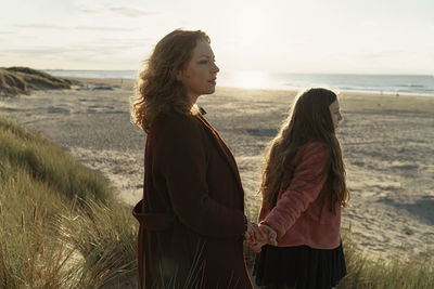 Woman standing on beach by sea against sky