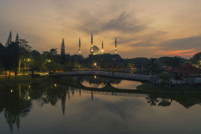 Scenic view of river by buildings against sky during sunset