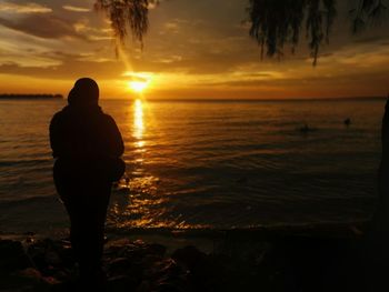 Silhouette man standing on beach during sunset