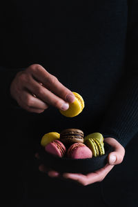 Close-up of hand holding candies against black background