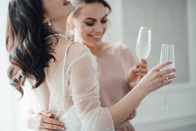 Bridesmaid and bride holding champagne flute