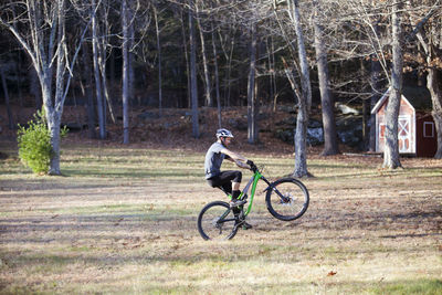 Side view of man mountain biking in forest