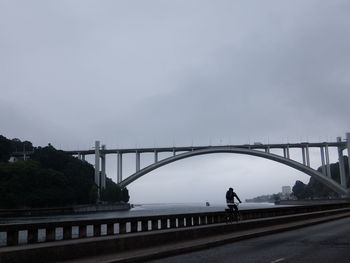 Bridge over river against sky in city