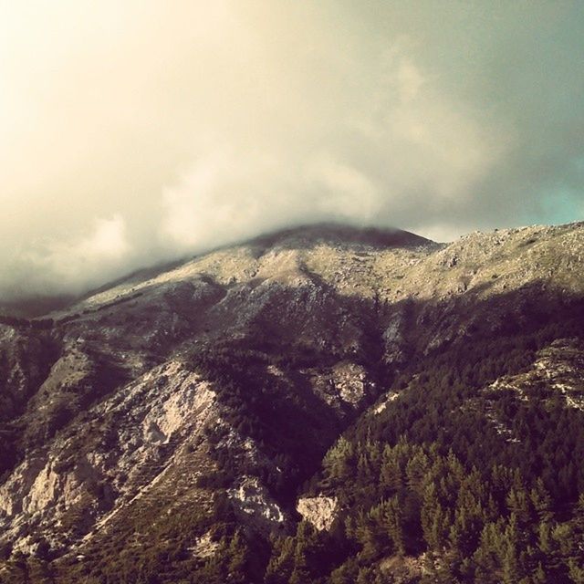 mountain, sky, cloud - sky, scenics, tranquility, tranquil scene, cloudy, mountain range, beauty in nature, nature, landscape, weather, cloud, non-urban scene, overcast, day, outdoors, rock - object, idyllic, low angle view