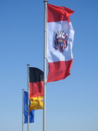 Low angle view of flags flag against clear blue sky