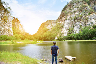 Rear view of man standing by lake against mountains