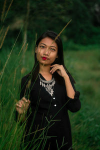 Portrait of young woman standing on field