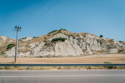 Road by mountains against clear blue sky