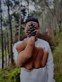 Midsection of man holding leaf in forest