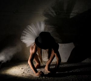 Girl wearing hat crouching in dirty room