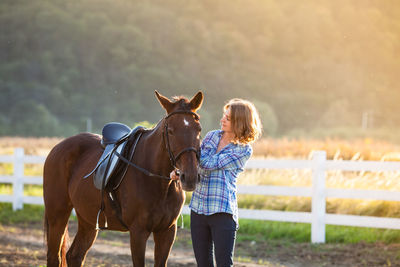 Woman with horse standing on land