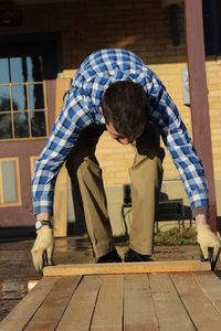 Full length of man making wooden boardwalk in yard