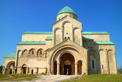 Female visitor at the church porch of bagrati cathedral gorgeous medieval church, kutaisi, georgia