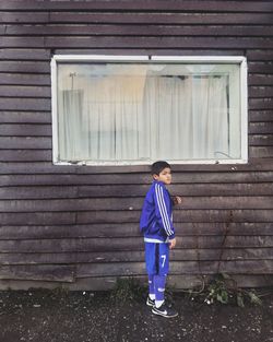 Full length of boy standing on window of building